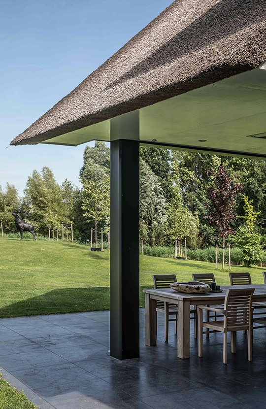 Woning met rieten dak en moderne elementen.