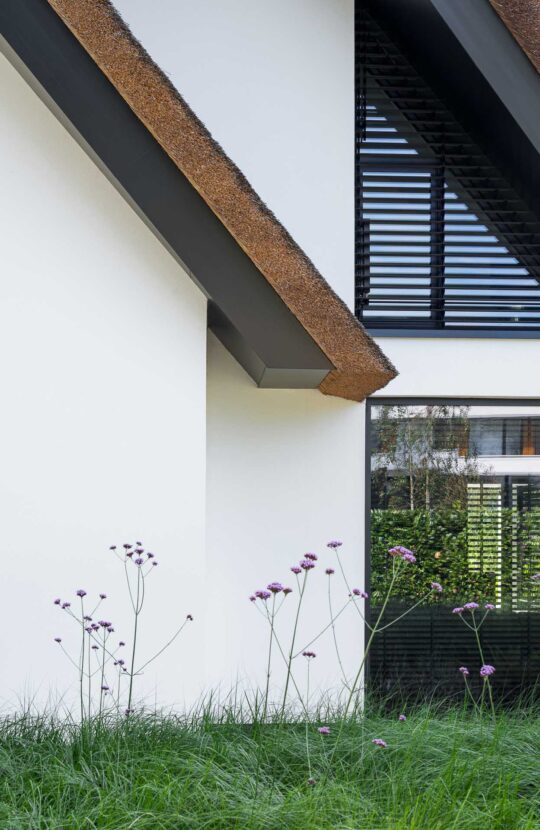 Wit gestuukte gevel van een luxe villa met rieten kap