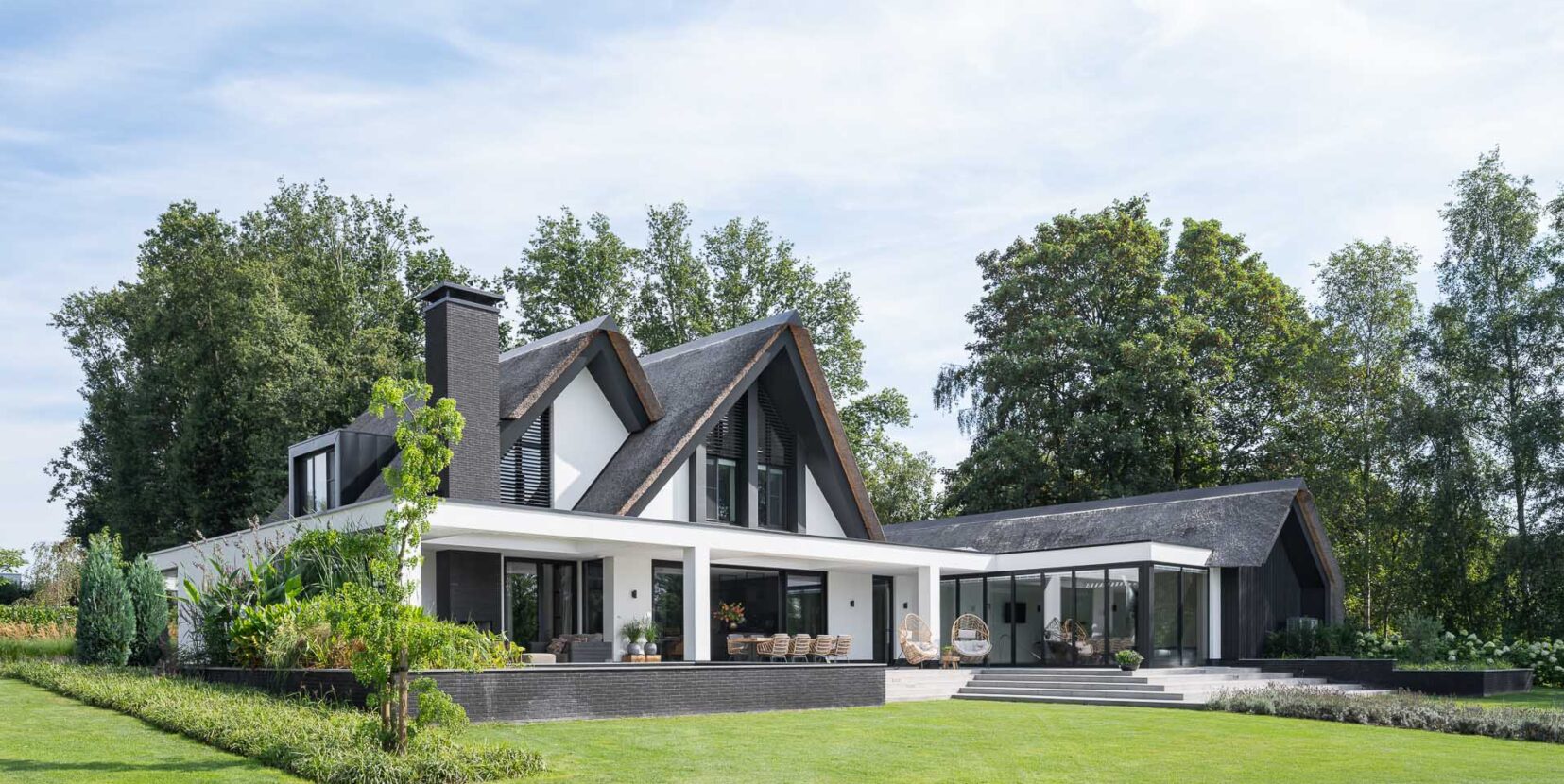 Bekhuis en KleinJan achterzijde witte villa met rieten kap