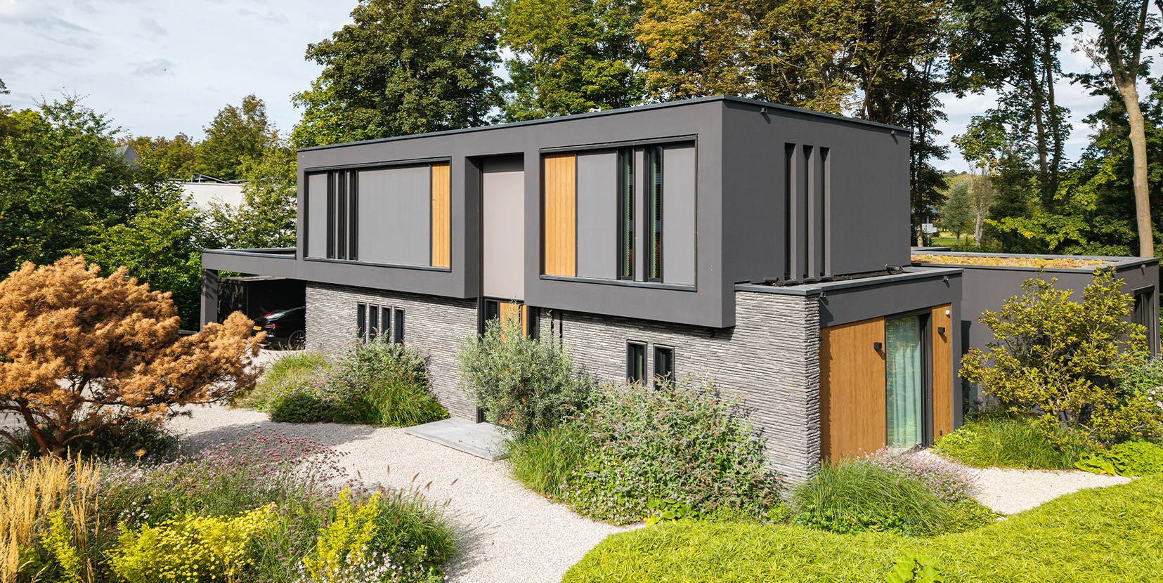 Kubistische villa omringd door bomen en veel groen.