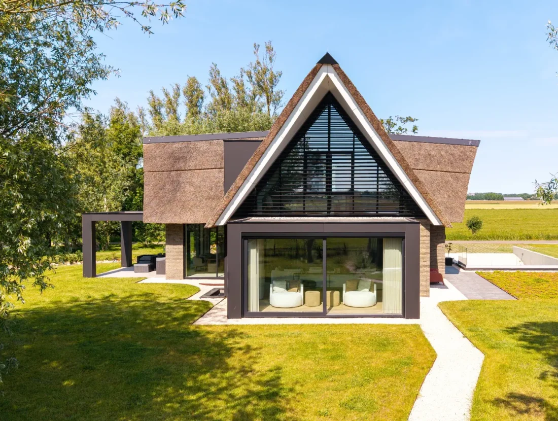 Dronefoto van rietgedekte villa met grijze gevelstenen