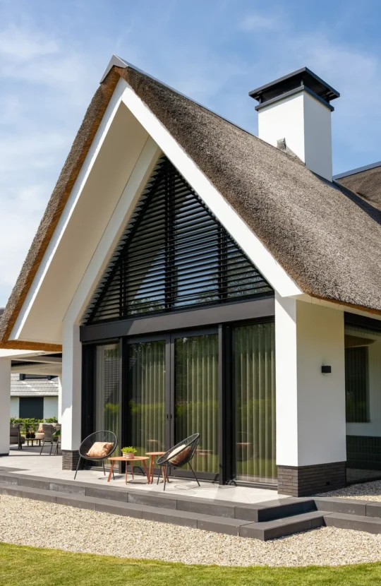 Rietgedekte villa, zijaanzicht met terras. Ontworpen door Bekhuis & KleinJan