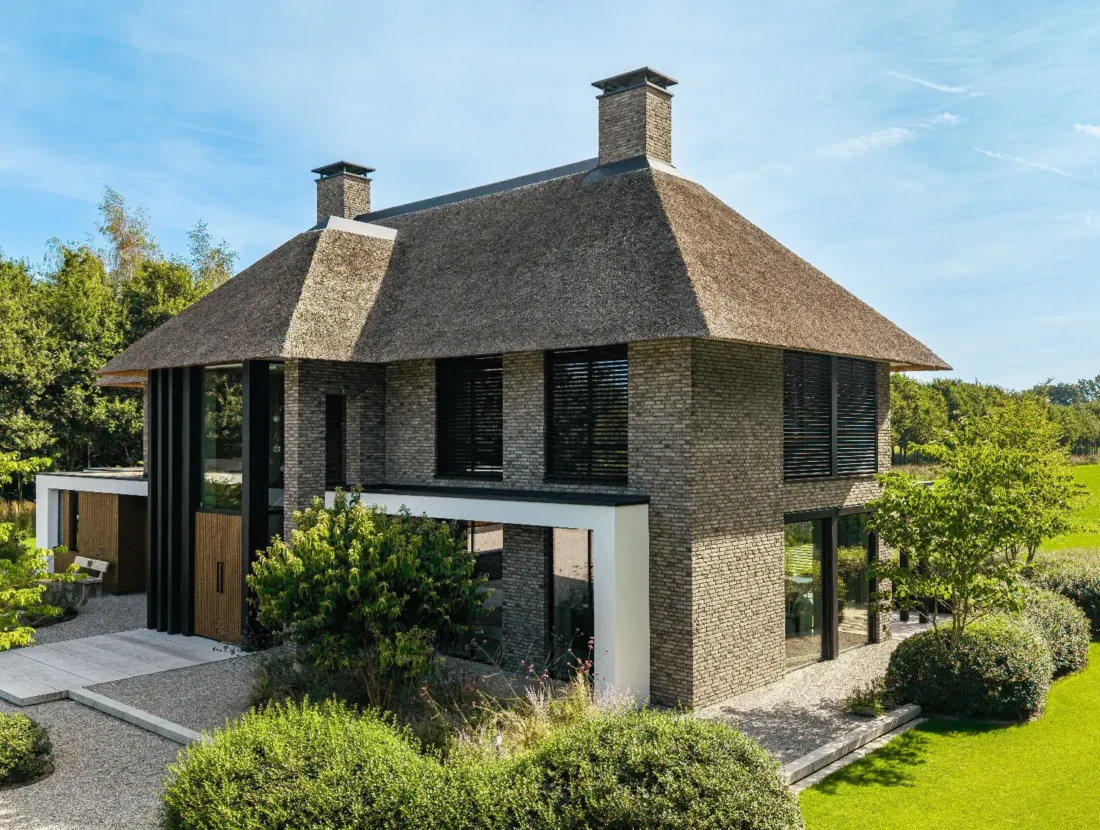 Dronefoto van een klassieke woning met riet en donker metselwerk