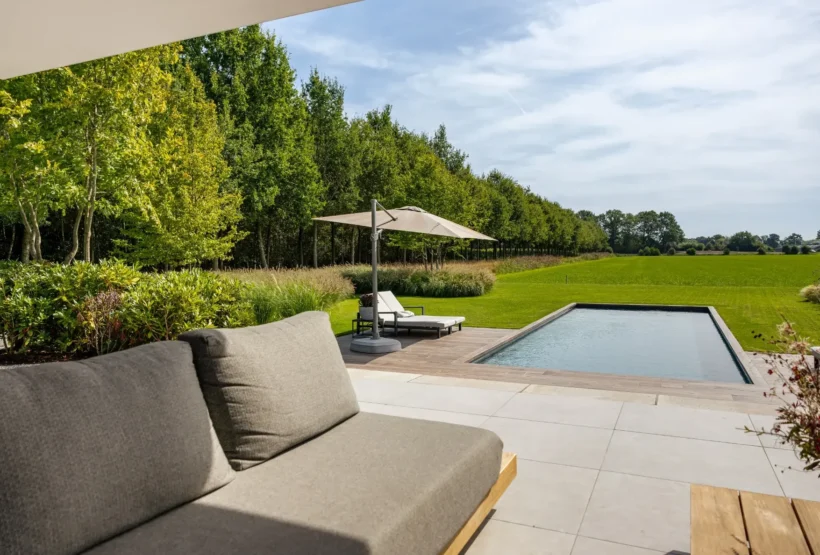 Uitzicht vanuit de overkapping op de tuin met zwembad